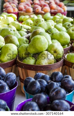 Table filled with fresh plums, pears and peaches for sale at local farmers market