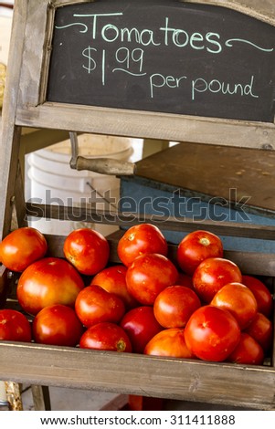 Fresh picked organic red tomatoes with chalkboard sign for sale  at local roadside produce stand