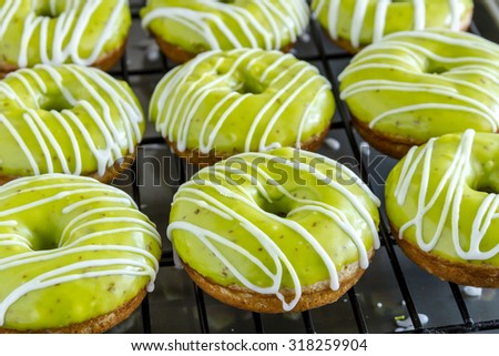 Homemade baked caramel apple donuts with green apple glaze sitting on wire baking rack after apple cider drizzle was applied