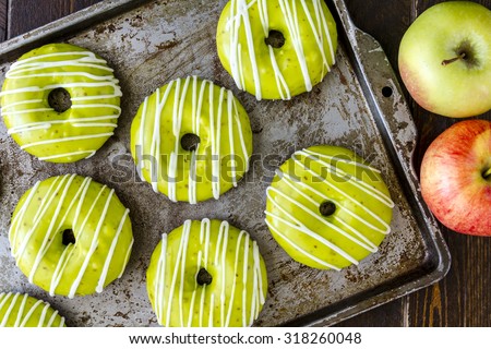 Baking pan filled with homemade baked caramel apple donuts with green apple glaze and apple cider drizzle and fresh apples on the side