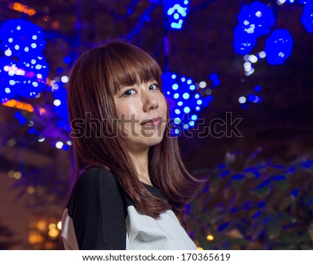Pretty Japanese female in front of blue bright decorations
