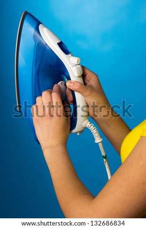 Houseworks, woman with pile of clothes for ironing, on blue background