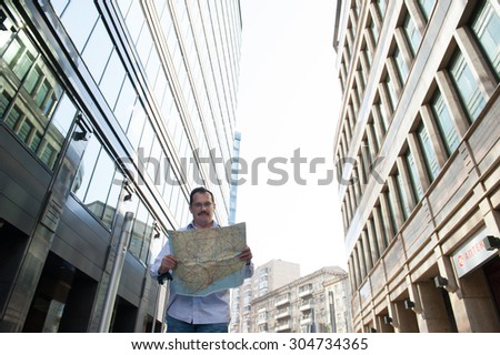 Man with blue bag lookig the way by city plan