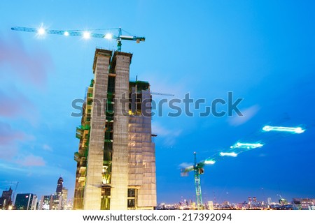 buildings under construction with cranes and illumination at dark night