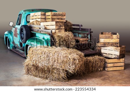 straw, stacks of old wood boxes and green truck for background
