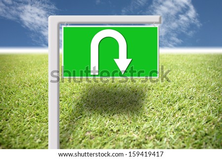 Green signs with arrows u-turn on grass.