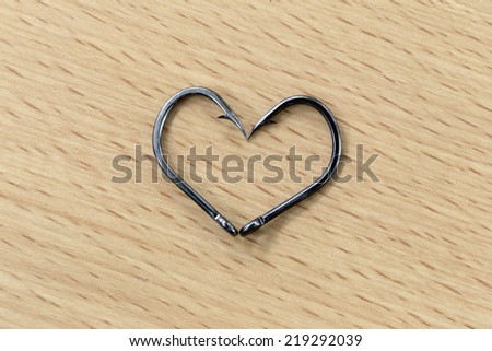 The black hooks placed heart symbols on wood background.