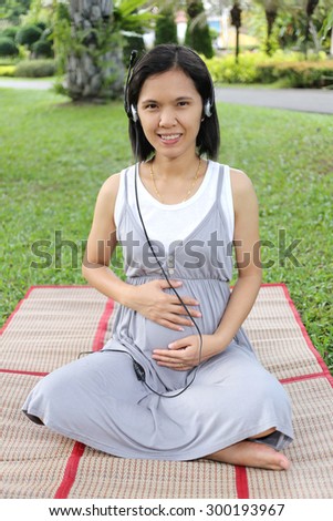 Thai Pregnant mom Was listening to music in the garden with bright emotional.