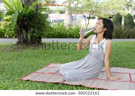 Thai pregnant mom was drinking water in the garden for good health.