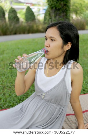 Thai pregnant mom was drinking water in the garden for good health.