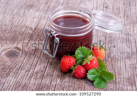 Jar of strawberry marmalade on vintage wood background