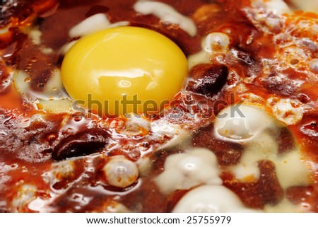 Eggs and red beans in the chili sauce fry on the skillet. Narrow depth of field.