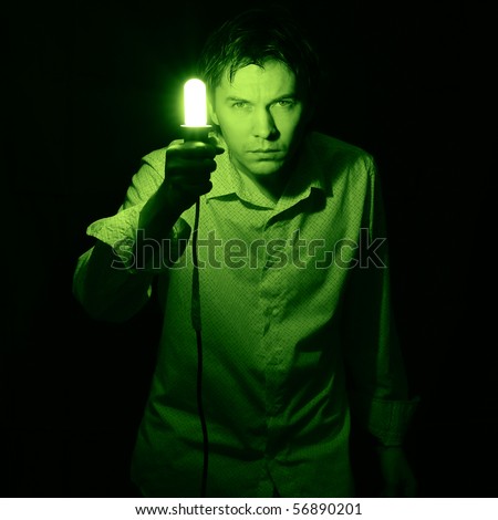 Man searching something in the dark with small electric lamp. Green tint.