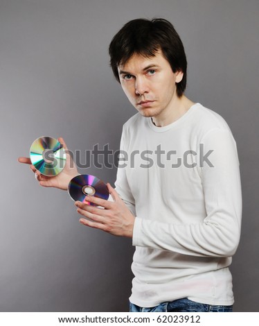 Man wearing white long sleeves shirt posing in the studio. With CD and DVD disk in the hands.