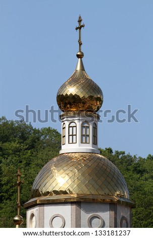 Gold cross on gold dome of church.