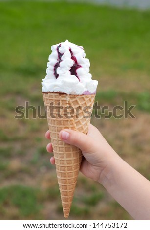 Ice cream in hand on natural green background