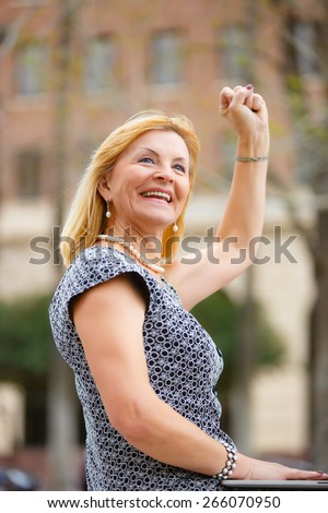 Portrait, Happy and Smiling old senior woman 60-65 years, looking to up, with gesture on face and raised hand up with fist in New York city park