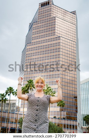 Portrait of happy laughing senior old woman 60-65 years with hands up, on city background