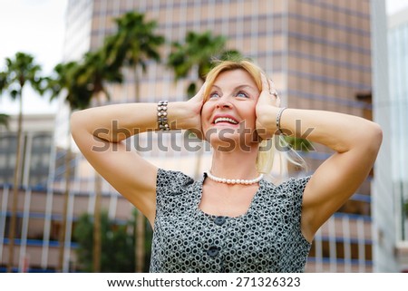 Happy senior old woman 60-65 years with emotions hands up and looking to sky, on city background
