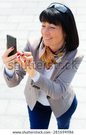 Ã¢??Ã?Â°lose up portrait Happy, cheerful and smile, brunette woman, excited by what she sees on cell phone, Facial expression, reaction. Business woman sending text message from her mobile