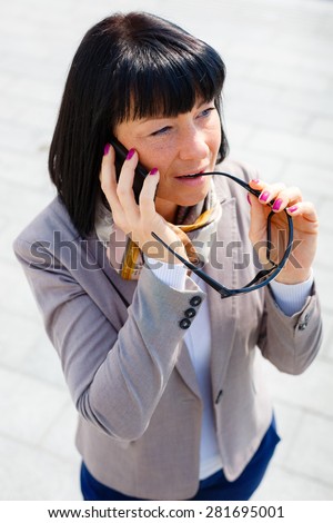 Business talk. Successful business woman in street speaks by cell mobile phone and focused on the conversation, spring mood