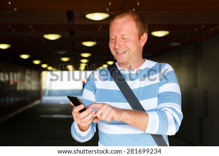 Man using smart phone on the street, smile stylish man of thirty five years with handbag,  on backlight bulbs background, Positive human emotion, facial expression