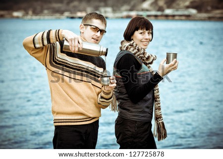 Tourists drink tea by the sea and lakes. Beautiful young couple relaxing on the beach