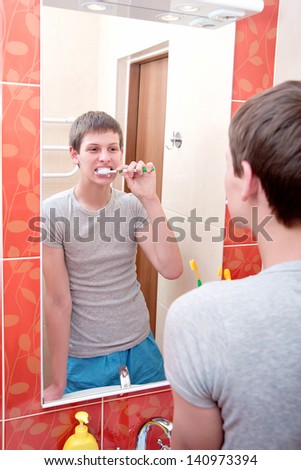 A man brushes his teeth in the bathroom..washing hands in bathroom.Wash basin with mixer tap and towels