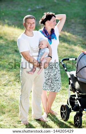 Parents of a child with a three-on nature. Happy family walking in the park. Beautiful young mother with a child in nature. Family resting on the air even so.