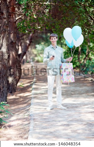 Young handsome man with gift and balloons. Gift Delivery