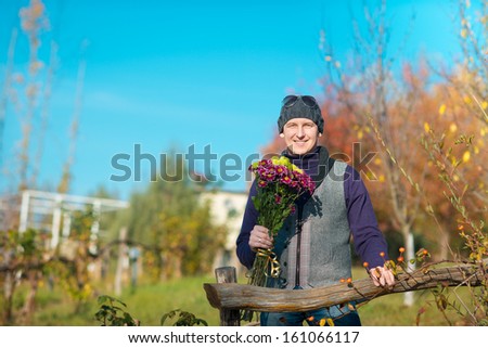 Beautiful  elegant man in a park in autumn. Man with flowers