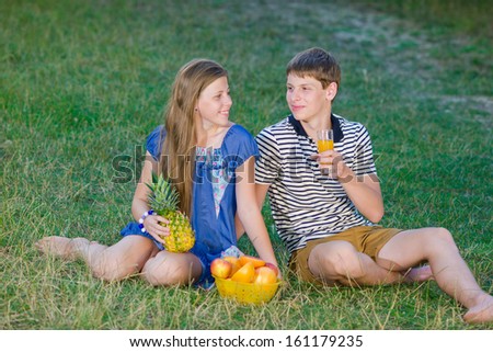 Portrait of happy young people. Children drink juice and eat fresh fruit.
