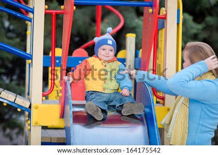 child rides in a baby slide.  cute toddler on slide on the playground. family in park