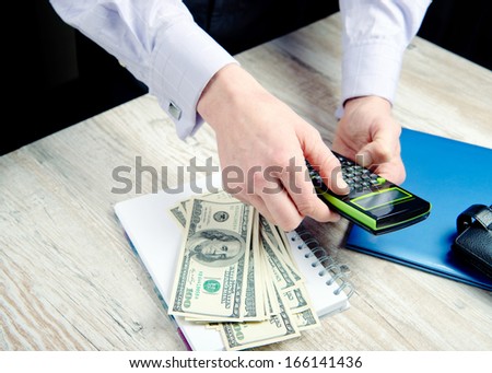 man counts money on calculator