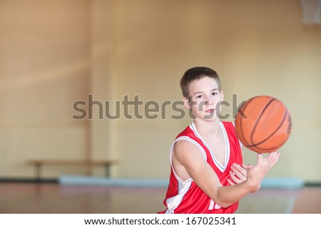 Basketball player with a ball in his hands and a red uniform.  Basketball player practicing in the gym