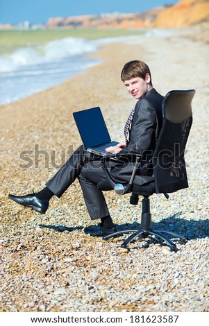 Freelancer working at a laptop. A man working on a computer at the seaside
