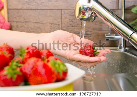 girl washes strawberries in the kitchen