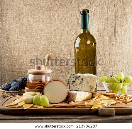 Various types of cheese, grapes, honey,  bottle of wine  composition