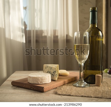 Various types of cheese, grapes, honey,  bottle of wine  composition