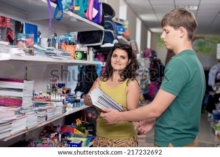 young man buys books and notebooks in the shop