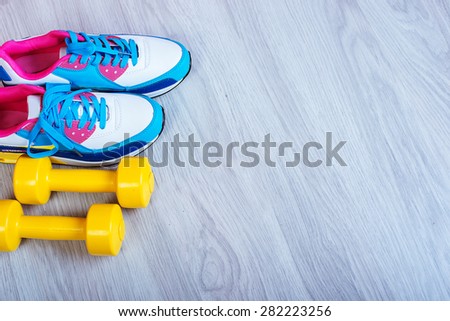 Sneakers and dumbbells fitness on a gray background. Different tools for sport