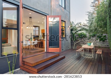 Double open french doors with seating arrangement in contemporary home with wooden terrace, open floor plan at night.