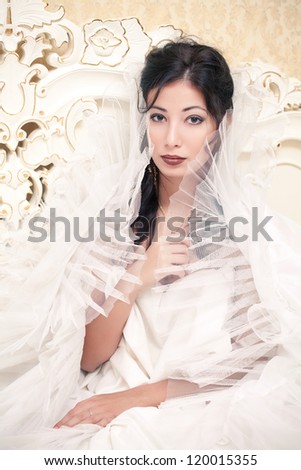 Vintage portrait of a beautiful queen like girl (bride) in the white bedroom. Retro style. Studio shot