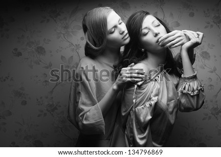 Portrait of two gorgeous young women in vintage dresses in a hotel room. Retro (Hollywood) style. Old classic movie. Film noir. Copy-space. Black and white (monochrome) studio shot