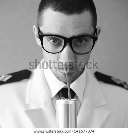 Portrait of a funny handsome hipster groom (dude) in trendy glasses drinking something from tin can through plastic sipper. Daylight. Close up. Black and white (monochrome) studio shot