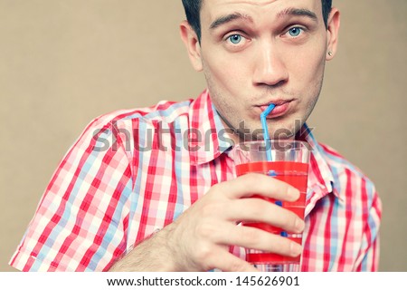 Funny portrait of a confused thoughtful blue-eyed hipster boy drinking his cocktail and posing over wooden background. Hipster style. Close up. Copy-space. Studio shot