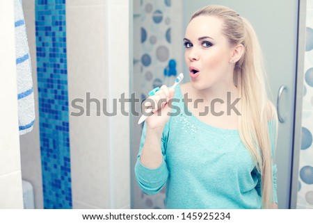Happy pregnancy concept. Beautiful young pregnant woman having fun: blonde holding her toothbrush and singing a song. Copy-space.  Indoor shot