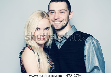 Portrait of happy and loving married couple posing together over light blue background. Casual urban style. Close up. Copy-space. Studio shot
