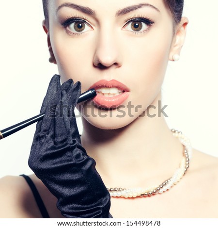Portrait of a fashionable model with a cigarette holder. Perfect skin. Great pearl accessories. Retro (hollywood) style. Close up. Studio shot