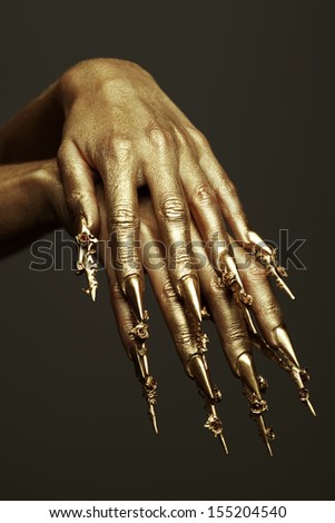 Art Manicure Concept. Beautiful golden hands with golden long arty nails. Close up. Studio shot